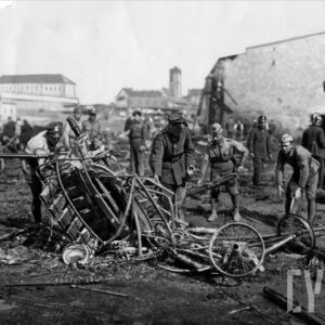 grupa mężczyzn porządkujących pozostałości z pogorzeliska, w tle fragmenty budynków przemysłowych