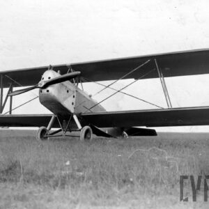 samolot dwupłatowy stojący na pustej trawiastej przestrzeni