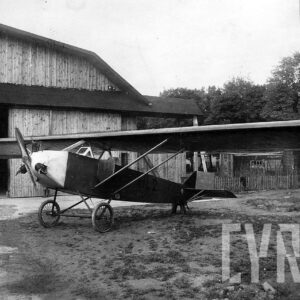 samolot na tle drewnianego budynku i drzew