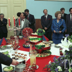 grupa elegancko ubranych osób stojących wokół stołu z przekąskami