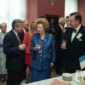 grupa starszych, elegancko ubranych osób z kieliszkami wina w dłoniach