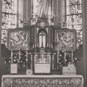 ołtarz przedsoborowy, zwieńczony figurą Matki Boskiej, nad tabernakulum krzyż, po jego bokach płaskorzeźby przedstawiające anioły, w głębi witraże zakończone półokrągłymi łukami