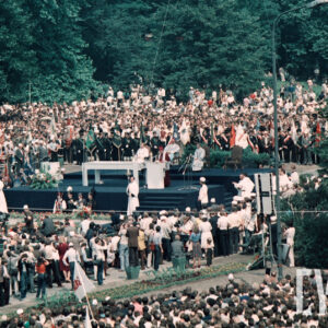 tłum osób zgromadzonych wokół prowizorycznego ołtarza, duża część z nich trzyma w rękach sztandary