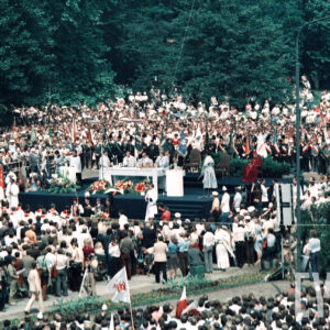 tłum osób zgromadzonych wokół prowizorycznego ołtarza, duża część z nich trzyma w rękach sztandary