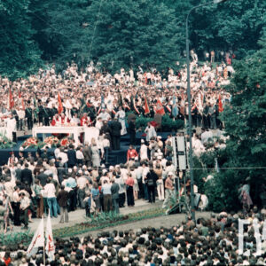 tłum osób zgromadzonych wokół prowizorycznego ołtarza, duża część z nich trzyma w rękach sztandary