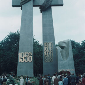 grupa osób stojących pod stalowym pomnikiem w formie dwóch krzyży i monumentu z głową orła