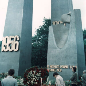 grupa osób stojących pod stalowym pomnikiem w formie dwóch krzyży i monumentu z głową orła