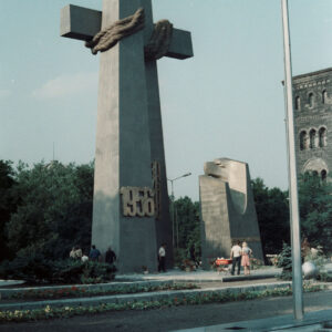 grupa osób stojących pod stalowym pomnikiem w formie dwóch krzyży i monumentu z głową orła