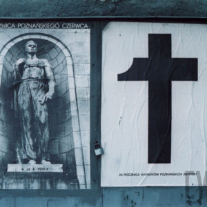 czarno-białe plakaty z napisami w języku polskim; jeden z nich przedstawia wizerunek krzyża z ukruszonym jednym ramieniem, drugi sylwetkę mężczyzny - robotnika