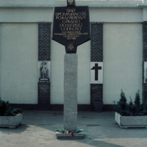 tablica ze złotymi literami ułożonymi w wyrazy, umieszczona na postumencie