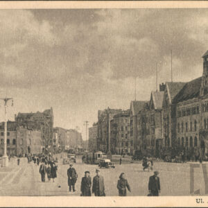 ulicą chodzą ludzie, jeżdżą samochody i tramwaje, po obu stronach ulicy budynki