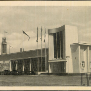 modernistyczny pawilon targowy z owalnym, wysokim wykuszem i pionowymi podziałami na elewacji, przed nim flagi na wysokich masztach