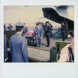 mężczyźni w mundurach niosą trumnę, za nimi otwarty właz samolotu