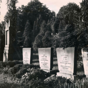 prostokątne płyty kamienne z wyrytymi cyrylicą napisami w języku rosyjskim w otoczeniu drzew i krzewów