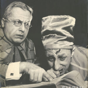 dwóch ekstrawagancko ubranych mężczyzn w średnim wieku spoglądających na książkę