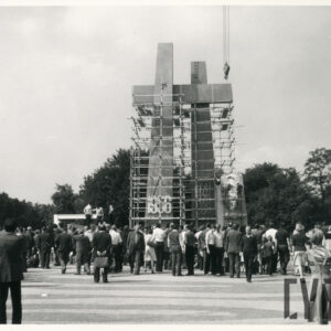 dwa wysokie krzyże ze wspólną belką, dookoła nich rusztowania, przed pomnikiem ludzie przyglądają się budowie