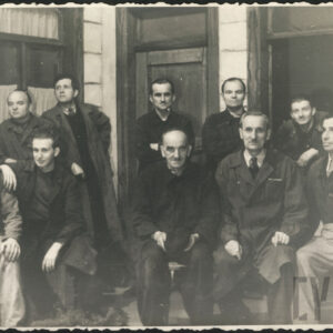 jedenastu mężczyzn pozujących przed wejściem do budynku 