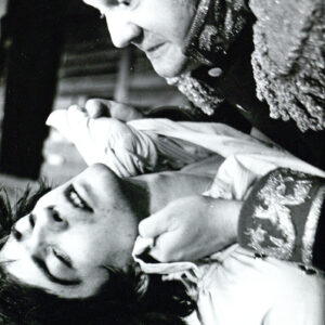 dwóch mężczyzn w kostiumach teatralnych, starszy z nich trzyma za koszulkę młodszego