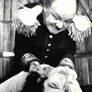 dwóch mężczyzn w kostiumach teatralnych, starszy z nich trzyma za koszulkę młodszego