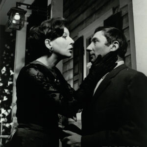 elegancko ubrani kobieta i mężczyzna w średnim wieku; kobieta trzyma dłonie na twarzy mężczyzny