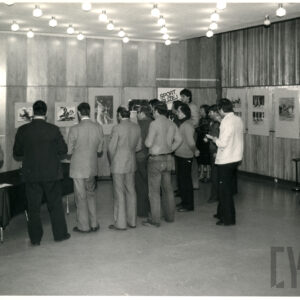 ludzie oglądający fotografie powieszone na ścianie