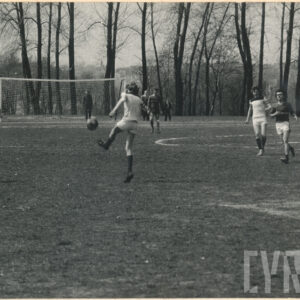 mężczyźni grają na trawiastym boisku w piłkę nożną, w głębi bramka