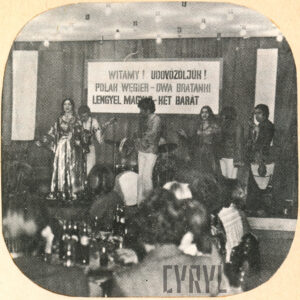 zespół artystyczny występuje na scenie, przed sceną widownia przy stołach