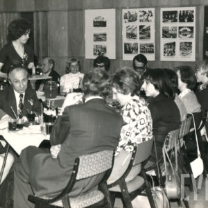 duża grupa osób siedzi przy zastawionych stołach