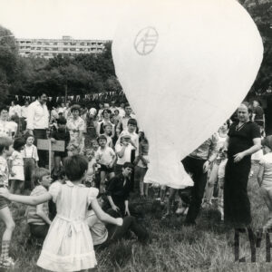 grupa dzieci stoi przy szykowanym do lotu balonie, pomiędzy dziećmi osoby dorosłe