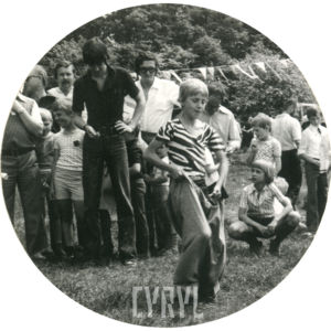 na pierwszy planie chłopiec biegnie w worku, w głębi grupa dzieci z dorosłymi osobami