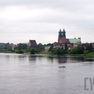 rzeka o podniesionym stanie, na jej brzegu widoczna zabudowa mieszkalna oraz monumentalny budynek katedry