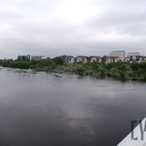 rzeka o podwyższonym stanie, dalej zatopione w niej drzewa, na brzegu zarysy budynków mieszkalnych