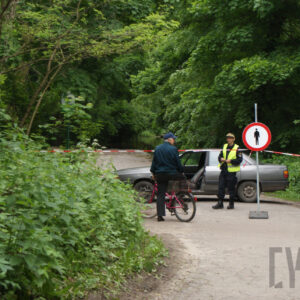 dwóch mężczyzn stojących przy taśmie i znaku zakazu wstępu, wokół drzewa 