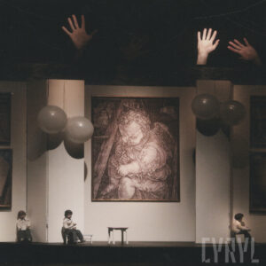 pośrodku obraz siedzącego małego dziecka, po jego obu stronach wiszą po dwa balony, na scenie na małych krzesełkach siedzą trzy lalki