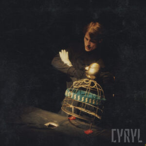 mężczyzna w czarnym stroju stoi z założonymi na piersiach rękami, przed nim stoi lalka