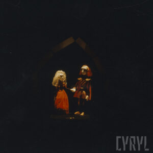 nieoświetlona scena, pośrodku punktowo oświetlone dwie lalki trzymające się za ręce