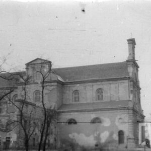 wieloczłonowa bryła budynku kościoła z urozmaiconym dachem i ozdobnymi szczytami przysłonięta nagimi konarami drzew