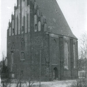 niewielki, wąski, ceglany budynek ze spadzistym dachem i sterczynami, w elewacji wysokie, wąskie okna i blendy