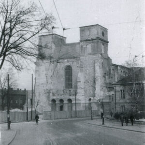 fasada katedry z utrąconymi w wyniku wojny wieżami, na pierwszym planie drewniane opłotowanie