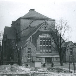 ceglany budynek z łamanym dachem i kilkoma szczytami z wejściem na osi