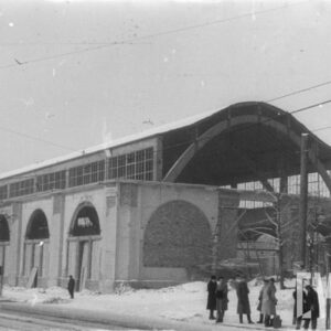 hala wystawiennicza z zaokrąglonym dachem i wielkimi oknami zakończonymi łukami, znacznie uszkodzona