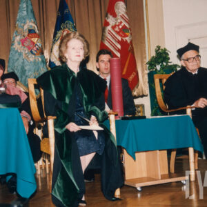 starsza kobieta ubrana w togę, w towarzystwie starszego mężczyzny w okularach i todze