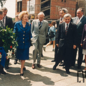 elegancka, starsza kobieta idąca w towarzystwie starszych mężczyzn ubranych w garnitury