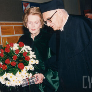 starsza kobieta ubrana w togę, w towarzystwie starszego mężczyzny w okularach i todze