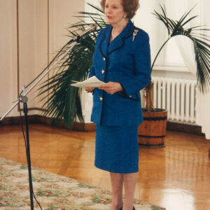 starsza, elegancka kobieta stojąca przed mikrofonem