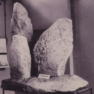 trzy nieregularne bryły różnej wielkości przypominające kształtem jaja na nieregularnym, chropowatym postumencie