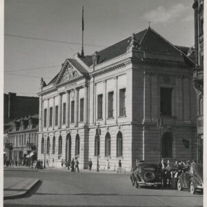 neorenesansowy, monumentalny gmach widziany z rogu ulicy, z zaparkowanymi zabytkowymi samochodami, widoczni przechodnie 