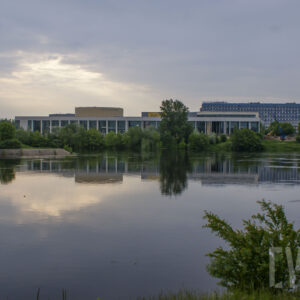 rzeka o wyraźnie podniesionym stanie, wzdłuż jej brzegów zielone, bujne drzewa oraz budynku