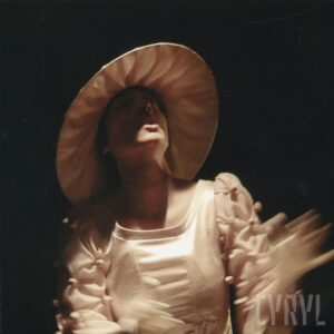 kobieta w kostiumie ze spektaklu, w jasnej sukience i kapeluszu z szerokim rondem