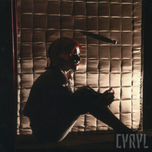 kobieta w kostiumie siedzi na pupie na scenie, lekko podświetlona